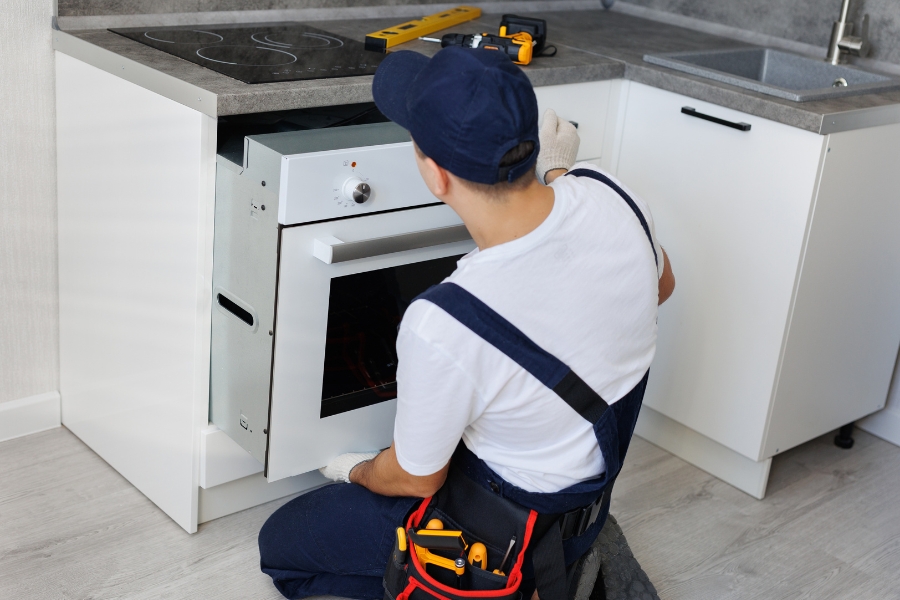 man repairing stove in home
